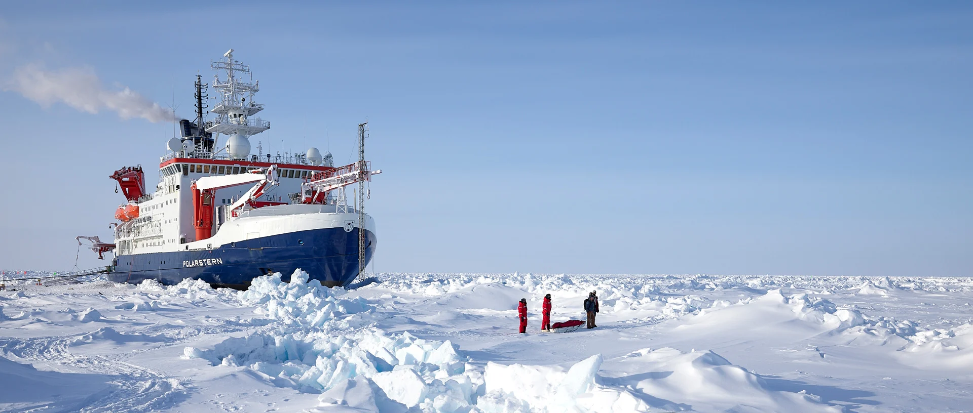 Foto dea Forschungsschiffs "Polarstern" von schräg vorne aufgenommen, während es einen Weg durch die antarktischen Eisschollen bricht. 