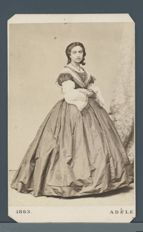 Ein Portrait von Adele Perlmutter auf dem sie ganz abgebildet ist. Sie trägt ein Kleid mit einem weiten Rock.