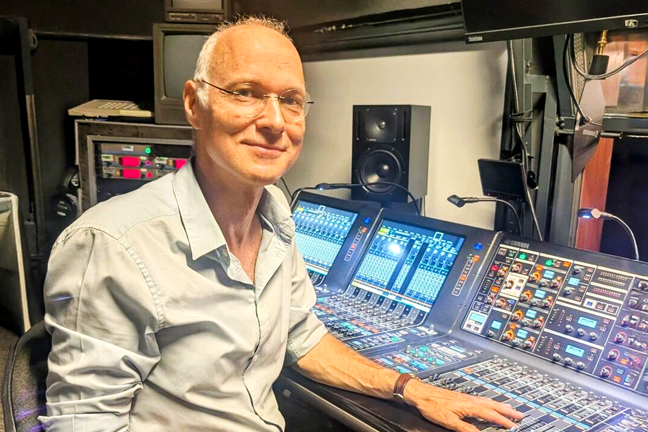 Edwin Pfanzagl-Cardone sits at a large audio mixing console in a studio and looks toward the camera.