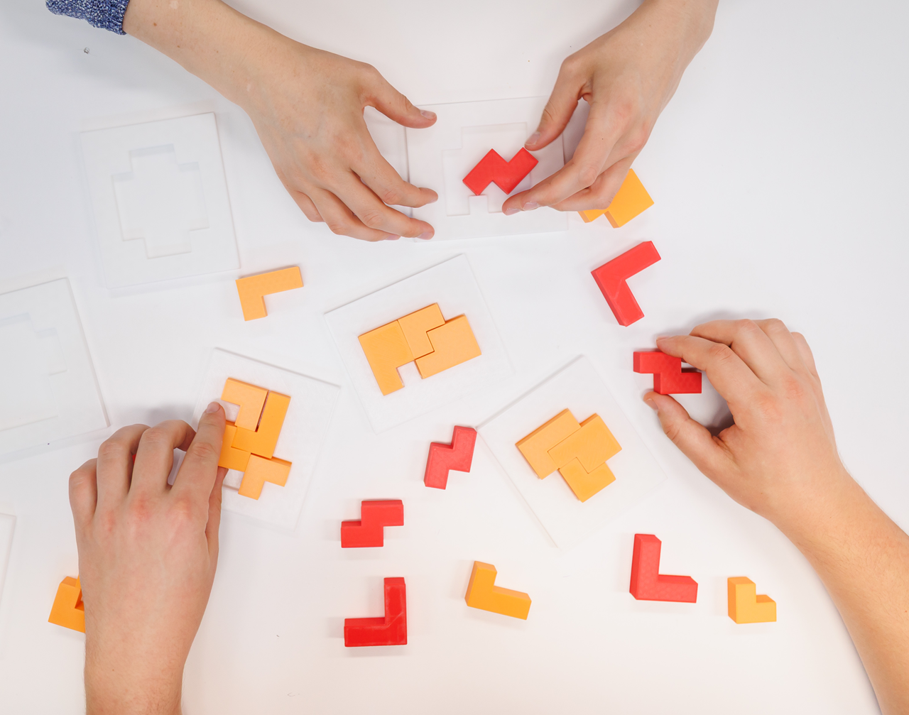 Children’s hands explore colorful puzzle pieces, solving shapes through play and collaboration.