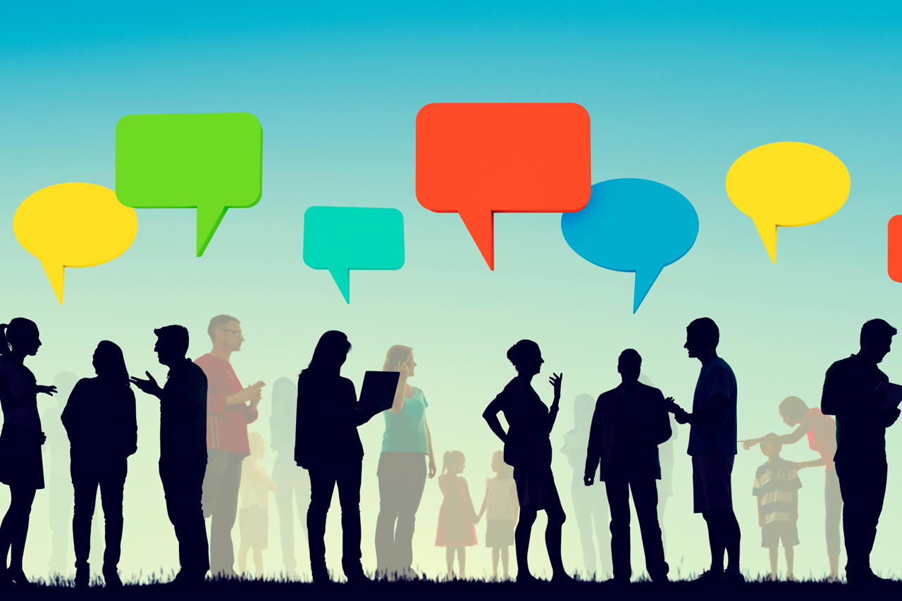 A group of silhouetted people are talking and interacting in an outdoor setting, with colorful speech bubbles floating above them to symbolize conversation and communication.