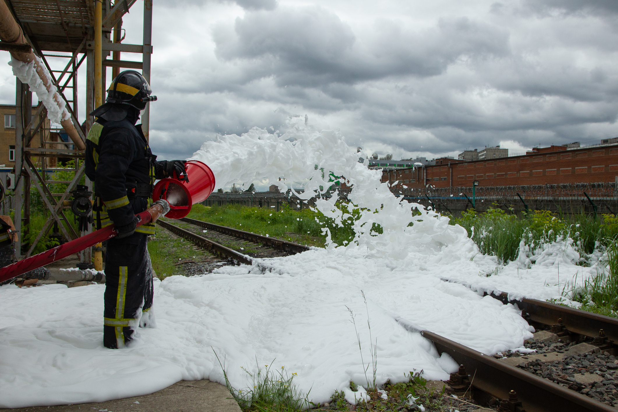 Ein Feuerwehrmann sprüht Löschschaum auf Eisenbahnschienen