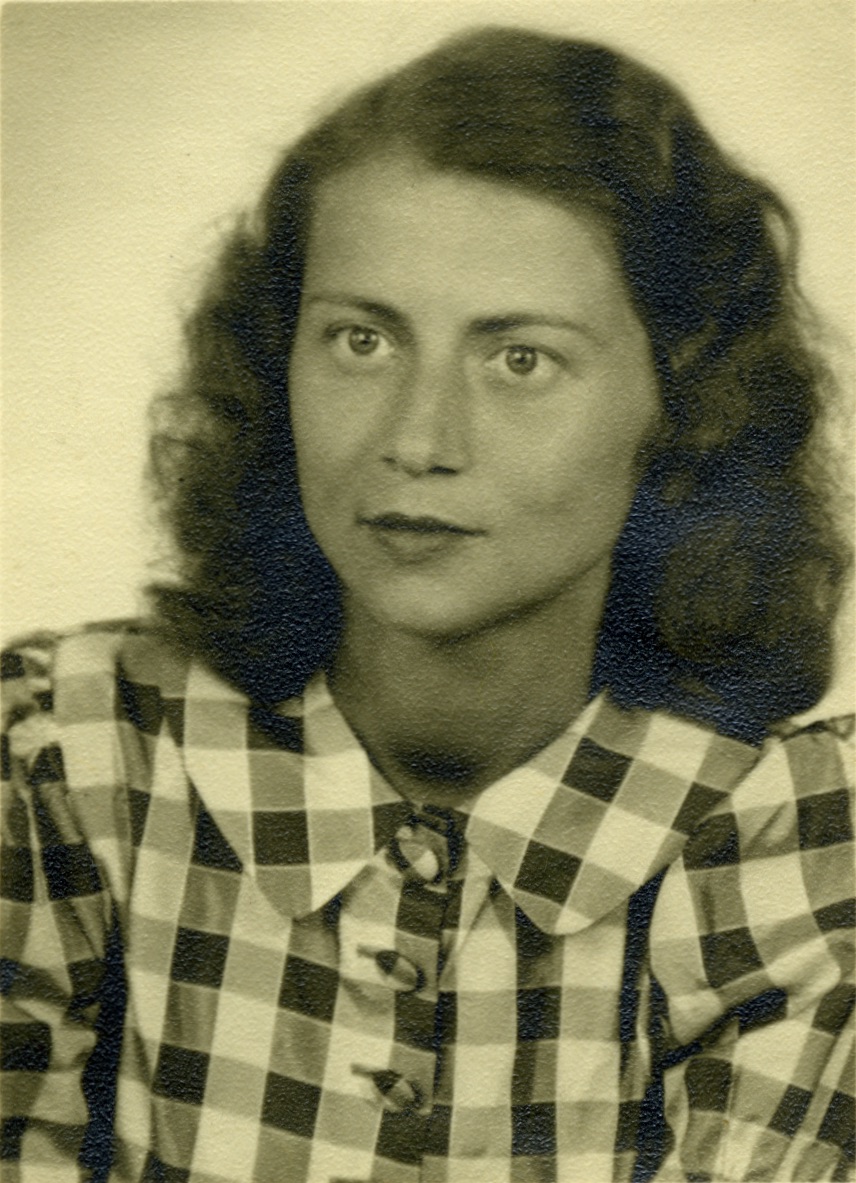 Das Bild zeigt eine junge Frau, Elfriede Kapeszky, mit langen dunklen Haaren und karierter Bluse.