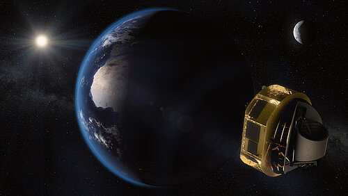 The image shows Earth from space, illuminated by the Sun, with the Moon and stars visible in the background. In the foreground on the right, the gold-colored ARIEL space telescope is floating.