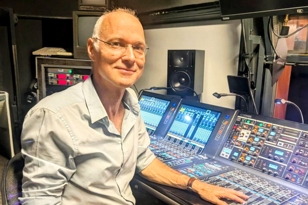 Edwin Pfanzagl-Cardone sits at a large audio mixing console in a studio and looks toward the camera.