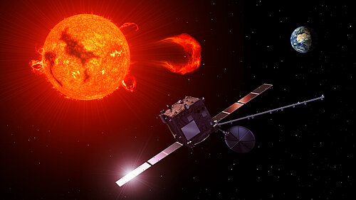 A space probe with solar sails floats in space against the backdrop of the glowing sun. In the background, Earth can be seen as a small sphere.