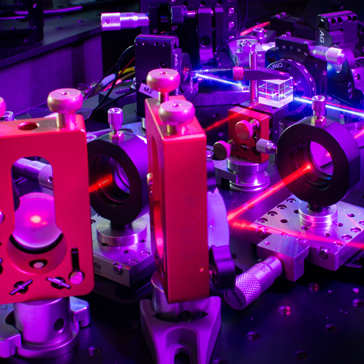 Quelle verschränkter Photonen mit starkem blauen Pumplaser und rotem Justagelaser am Institut für Quantenoptik und Quanteninformation der ÖAW. Der blaue Laser interagiert mit einem nichtlinearen Kristall und produziert dabei verschränkte Photonenpaare, die dem Pfad des roten Justagelasers folgend in optischen Glasfasern gekoppelt werden. 