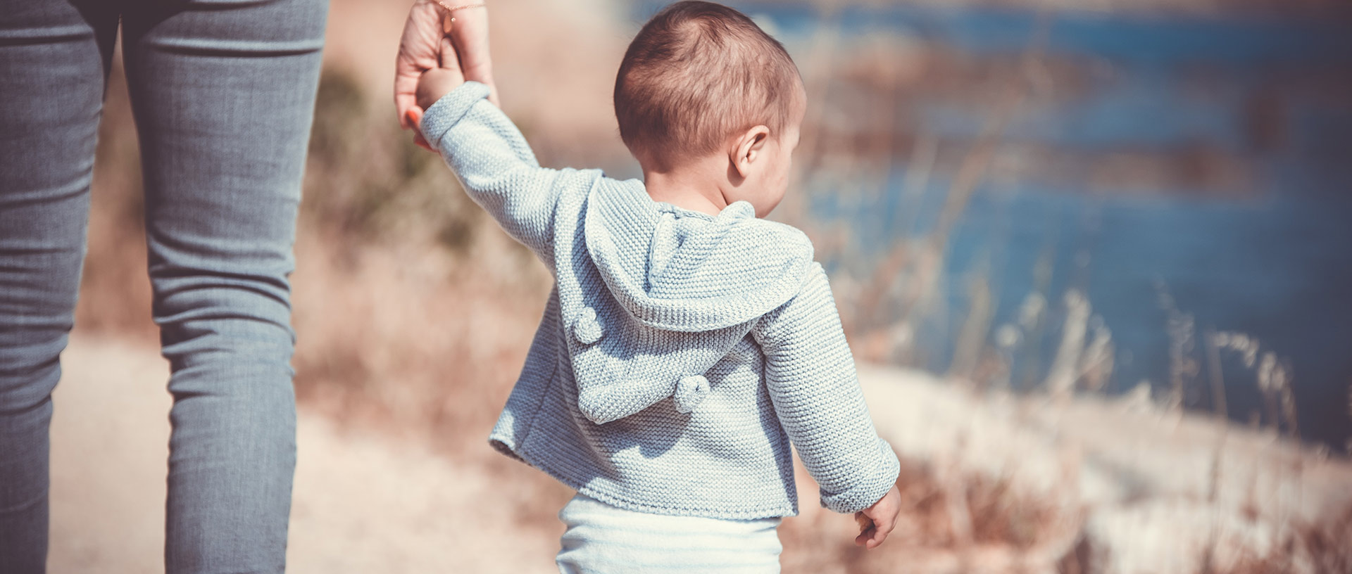Ein gehendes Kleinkind hält die Hand der Mutter Ein gehendes Kleinkind hält die Hand der Mutter