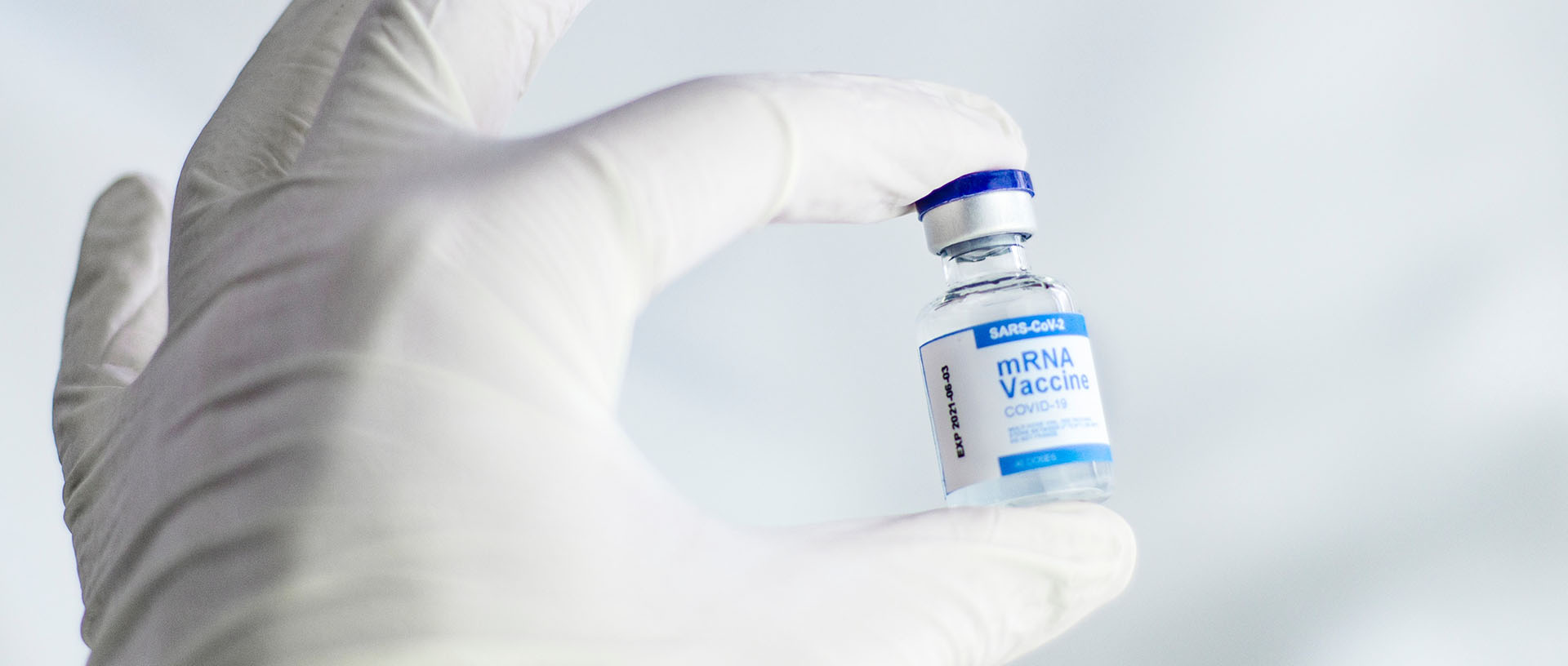 Hand, die eine Ampulle eines mRNA-Impfstoffes hält