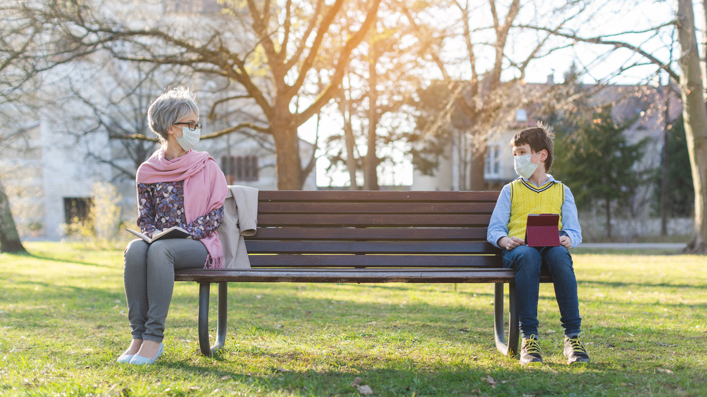 Eine ältere Frau und ein junger Knabe sitzen auf einer Parkbank. 