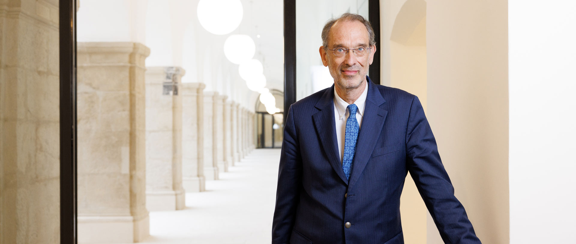 Heinz Faßmann Heinz Faßmann steht vor einem Arkadengang.
