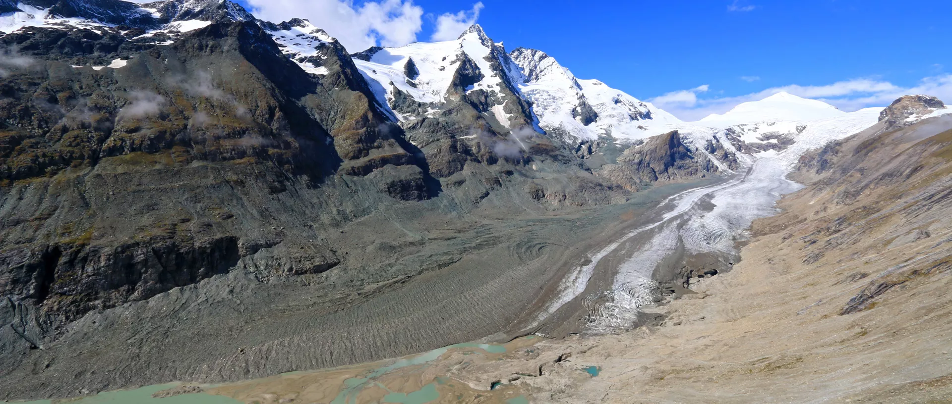 Eine Gletscherzunge vor einem fast schneefreien Gletscher.