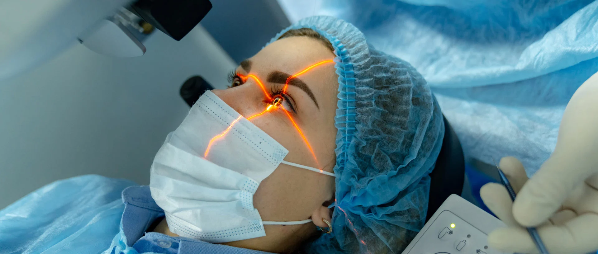 Eine Frau liegt unter einem medizinischen Gerät, das ihr Auge mit einem Laserstrahl abtastet