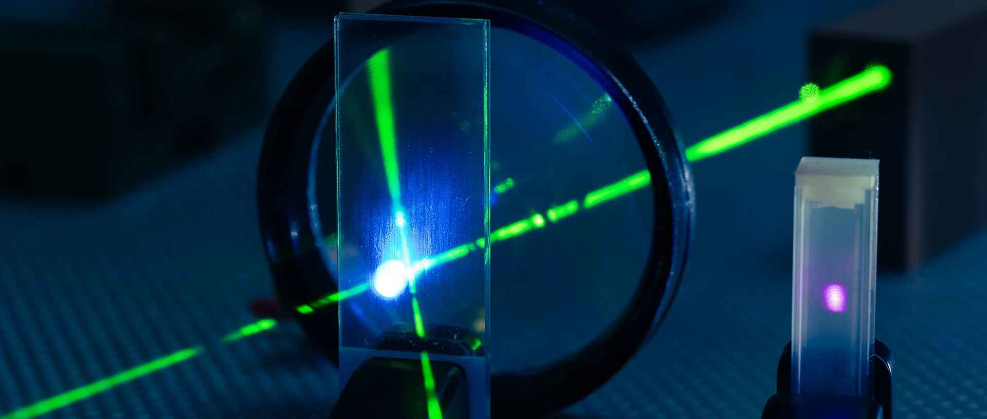 Fotografie einer Lupe, durch die ein grüner Laserstrahl geschickt und gebrochen wird