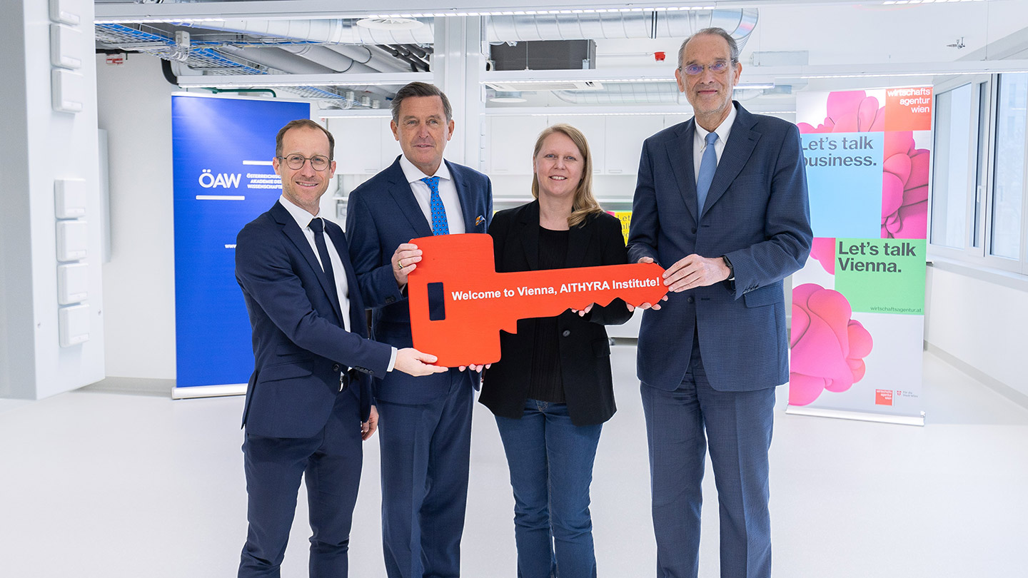 Gruppenfoto mit einem symbolischen, übergroßen Schlüssel, den die vier abgebildeten Personen in Händen halten