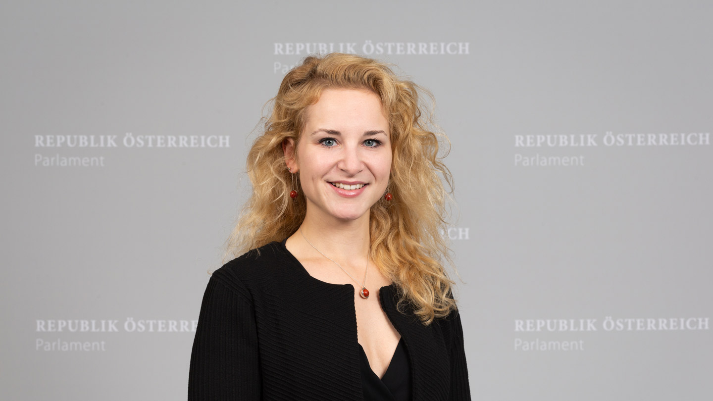 Porträtfoto von Eva-Maria Holzleitner vor einem grauen Hintergrund mit dem Schriftzug "Republik Österreich"