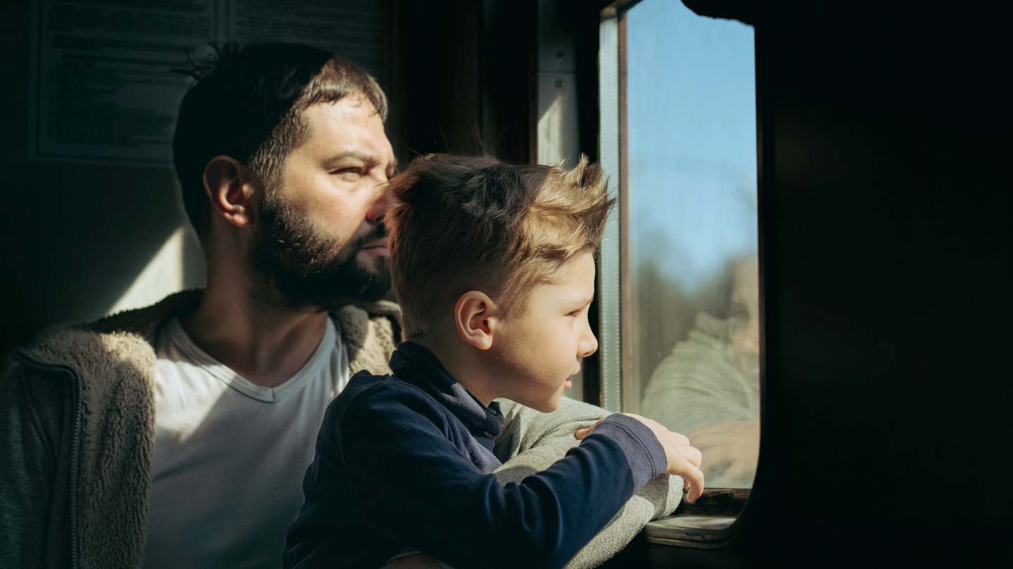 Ein Mann und ein Kind blicken aus dem Fenster eines fahrenden Zuges
