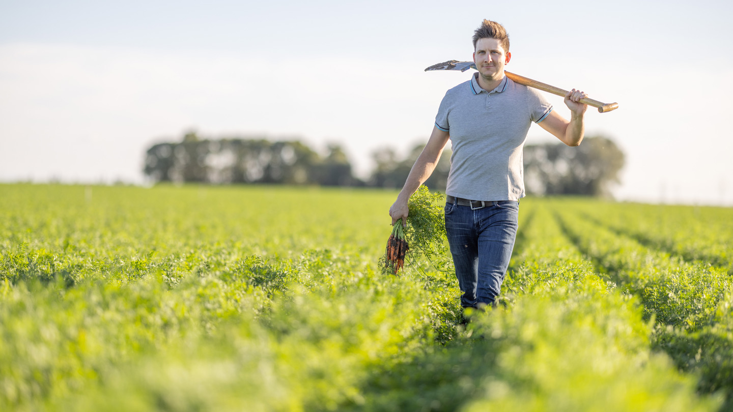 Ein Bauer steht mit Schaufel auf einem Feld