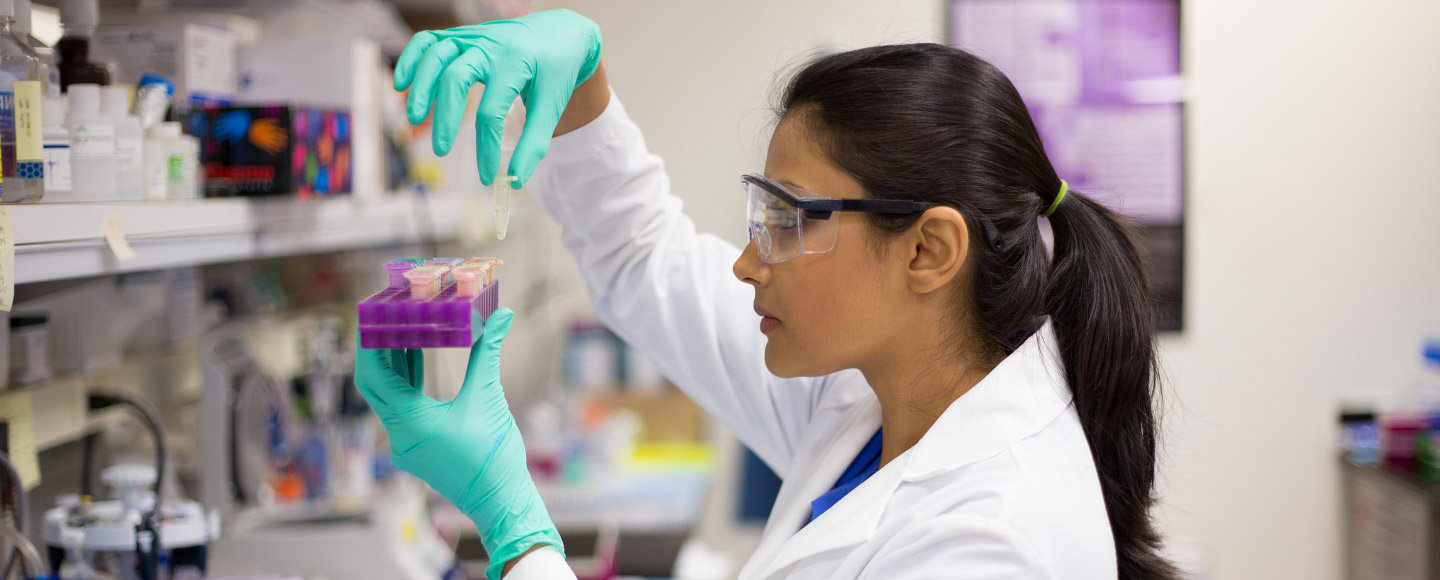 Eine Wissenschaftlerin hält in einem Labor ein Reagenzglas
