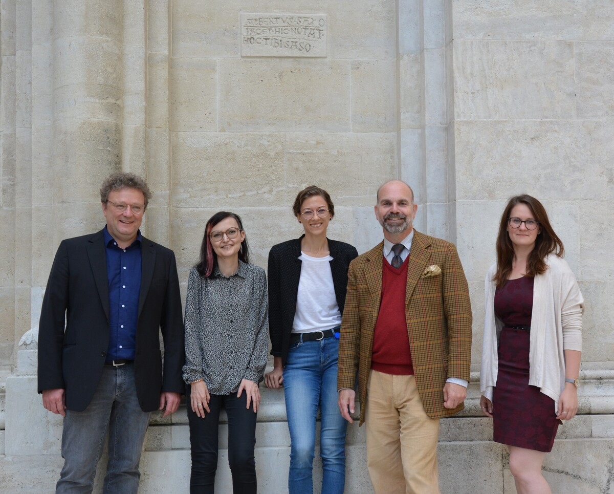 The PREMISES team (from left to right: Sabine Miesgang, Edith Kapeller, Andreas Zajic, and Julia Anna Schön) meets Klosterneuburg librarian Martin Haltrich beneath a stone tablet commemorating Albertus Saxo, librarian of the abbey in the late 13th century.