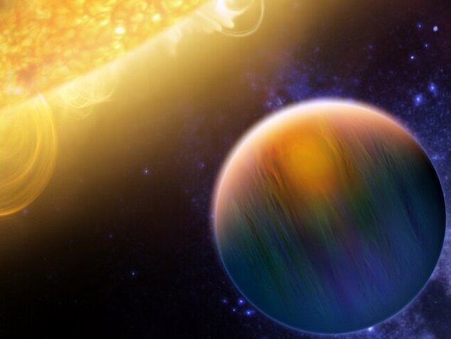 The artist's rendering depicts the exoplanet HD 189733b as a dark blue sphere with a reddish glow against the backdrop of dark space. In the foreground on the left is a large portion of a brightly shining, yellow-orange star with active solar flares.