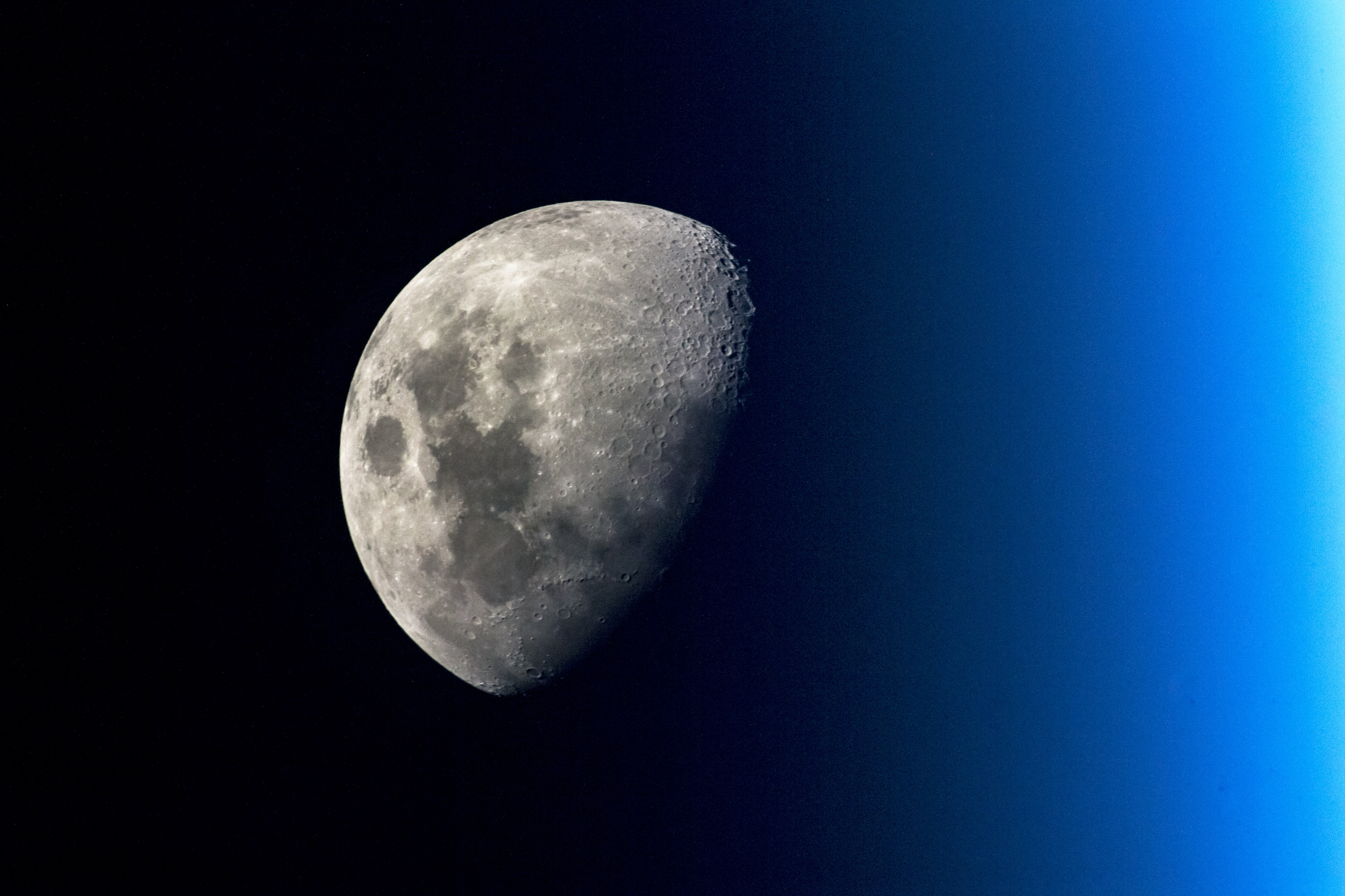 Im Hintergrund des Fotos ist ein Farbübergang von hellblau bis schwarz zu erkennen. Links, auf der dunkleren Seite, sieht man den Mond.