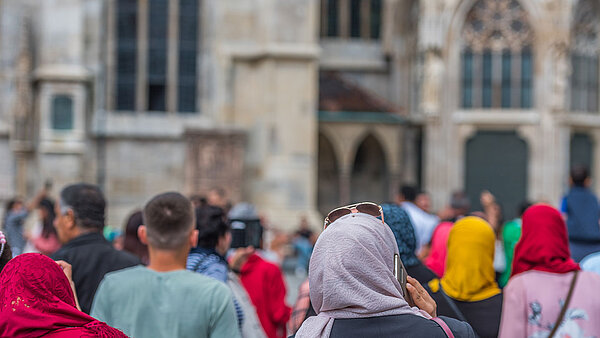 Eine Gruppe, darunter mehrere Frauen mit Kopftuch, blicken auf die Fassade des Stephansdoms