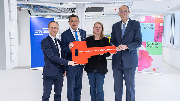 Gruppenfoto mit einem symbolischen, übergroßen Schlüssel, den die vier abgebildeten Personen in Händen halten