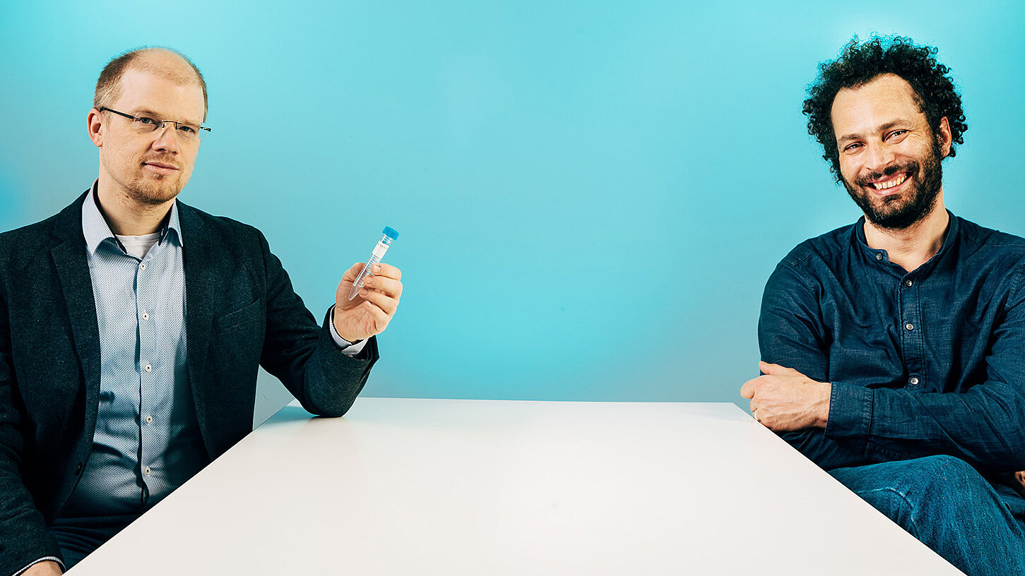 Andreas Bergthaler (links) und Julius Brennecke (rechts) mit einem kleinen aber für die Bekämpfung der Pandemie nicht unwesentlichen Gegenstand: Einem Probenröhrchen, das für Virustests verwendet werden kann. © ÖAW/Klaus Pichler