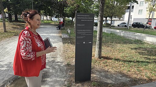 A Woman is standing at a Commemorative plaque