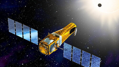 A golden, cylindrical satellite with two large, blue solar panel wings floats in deep space. In the background, a bright sun shines in the upper right corner, with a small, dark planet silhouetted against it as it transits across the sun.