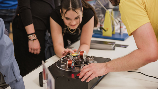 Ein Mädchen beugt sich über einen elektrischen Apparat mit Metallspulen