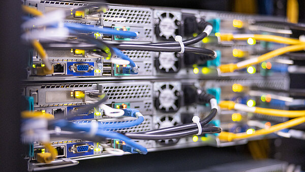 Foto von der Rückseite eines Computer-Racks mit zahlreichen angesteckten bunten Kabeln