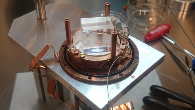 Offenes Detektormodul des COSINUS-Experiments während des Zusammenbaus. Zu sehen ist der kubische Natriumiodid-Kristall und seine aus Kupfer gefertigte Halterung. Offenes Detektormodul des COSINUS-Experiments während des Zusammenbaus. Zu sehen ist der kubische Natriumiodid-Kristall und seine aus Kupfer gefertigte Halterung.