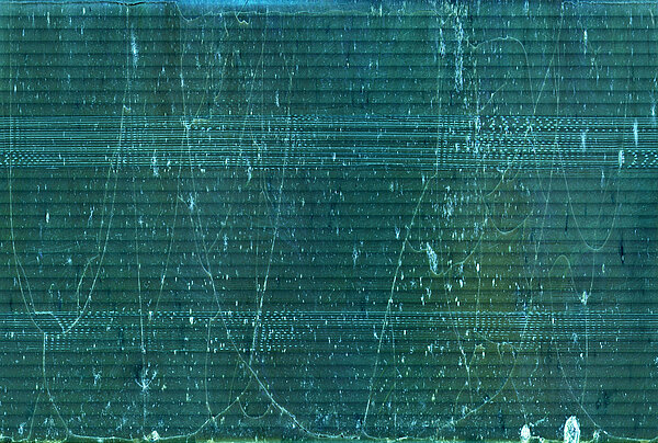 Die blaugrüne Grafik zeigt die Schallplattenrille mikroskopisch vergrößert auf einer X-Achse angetragen. Sichtbar sind lange Brüche in der Wachsschicht.