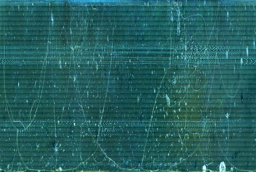 Abb. 3: Die blaugrüne Grafik zeigt die Schallplattenrille mikroskopisch vergrößert auf einer X-Achse angetragen. Sichtbar sind lange Brüche in der Wachsschicht.