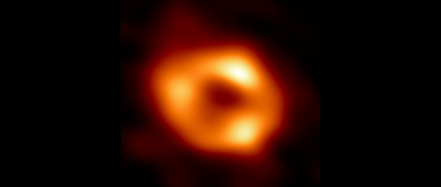 Fotografische Aufnahme des Schwarzen Lochs: Ein diffus orangener Ring umkreist einen dunklen Mittelpunkt