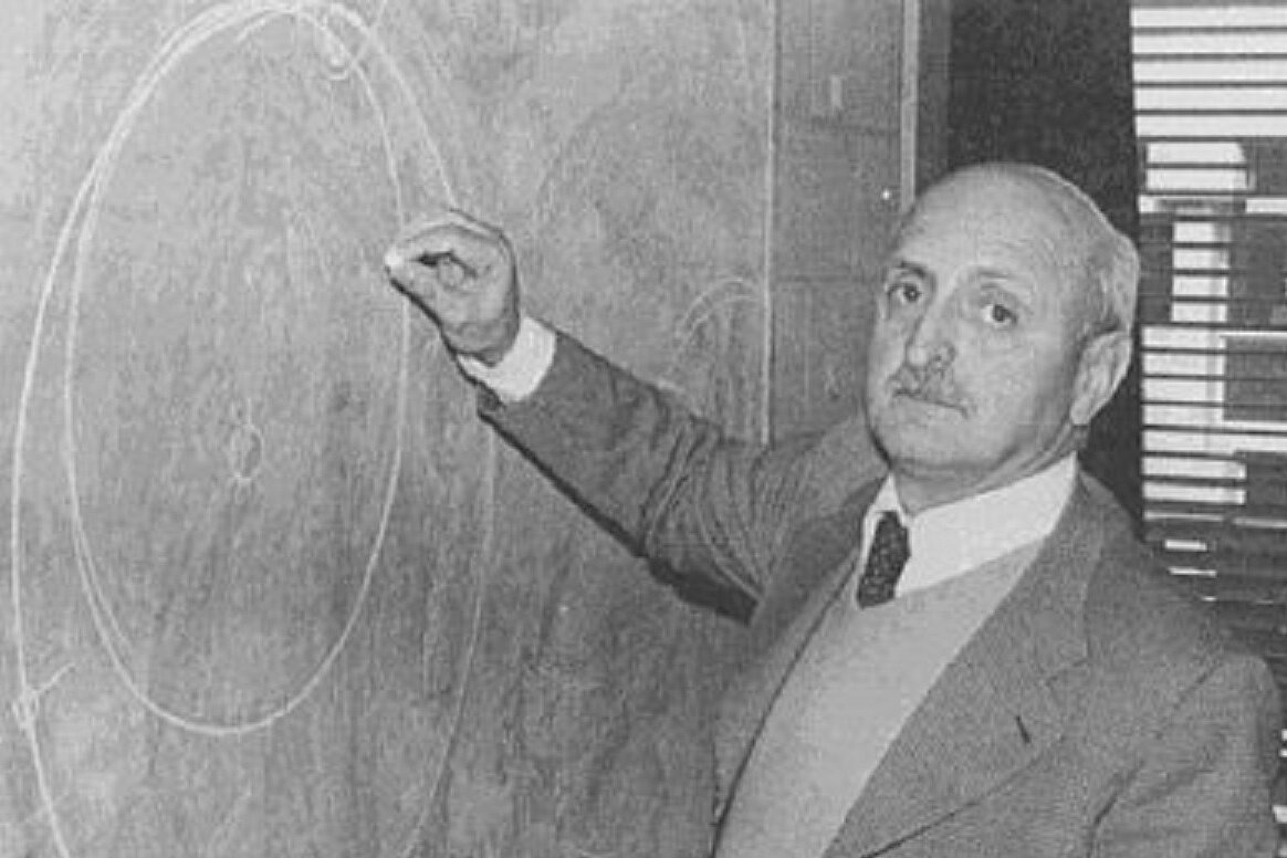 Schwarz-Weiß-Foto des Wissenschaftlers Giuseppe Colombo beim Zeichnen von Planetenumlaufbahnen an einer Tafel.