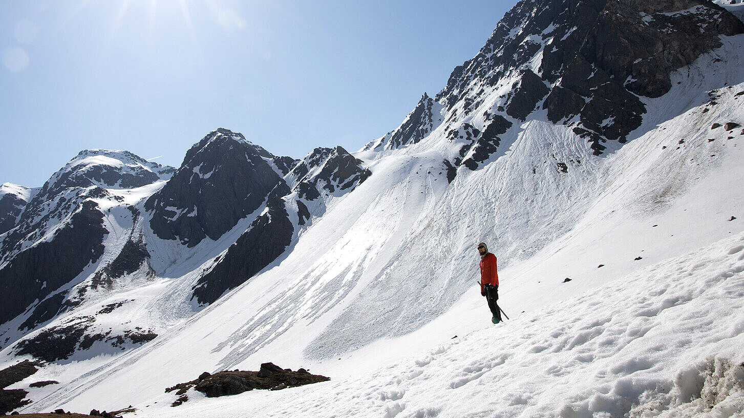 Ein Mann steht alleine auf einem verschneiten Berghang Ein Mann steht alleine auf einem verschneiten Berghang