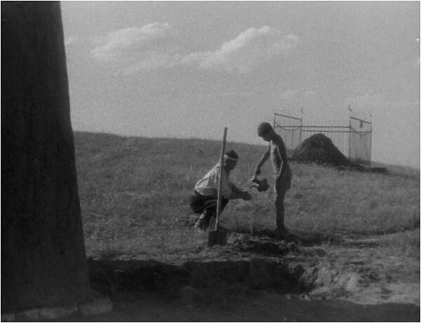 A greyscale photo of two men in a rural countryside