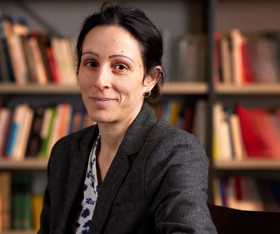 Frau mit dunklen Haaren, Dr. Ariane Sadjed, vor Bücherregal